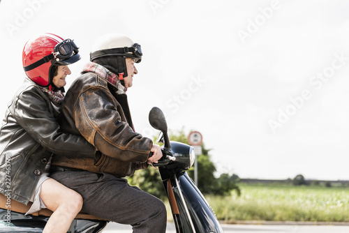Happy senior couple riding motor scooter