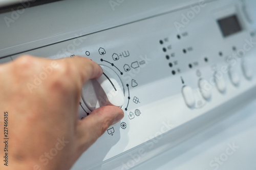 closeup of hands on washing machine dashboard