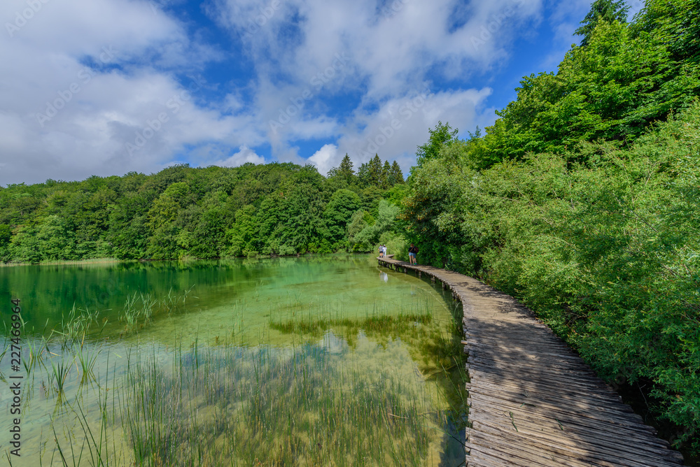 PLITVICE NATIONAL PARK, CROATIA - JUNE 8, 2018: Tourist group by the lake in the Plitvice Lakes National Park. PLITVICE NATIONAL PARK, CROATIA - JUNE 8, 2018: Tourist group by the lake in the Plitvice Lakes National Park.