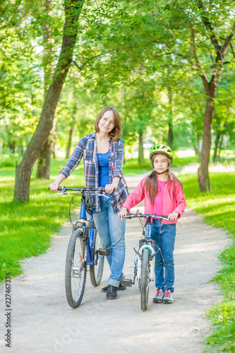 Mom and daughter are cycling in the park together