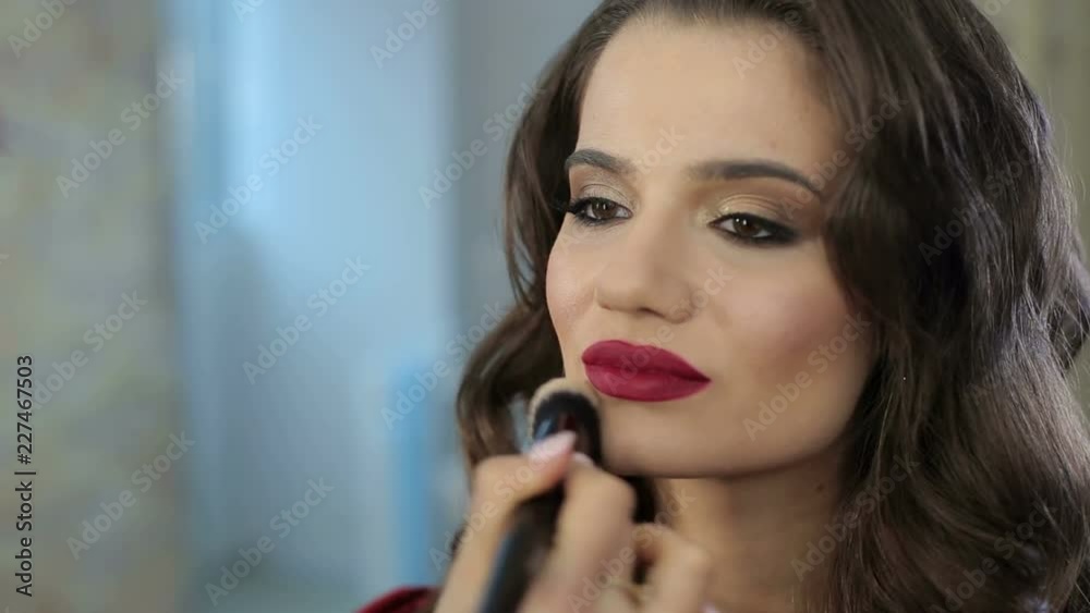 Make-up artist doing make-up for beautiful girl in the salon, beauty concept and style. Close-up. Portrait of a girl with a hairdo and bright professional make-up in a beauty salon. Make-up artist doing make-up for beautiful girl in the salon, beauty concept and style. Close-up. Portrait of a girl with a hairdo and bright professional make-up in a beauty salon.
