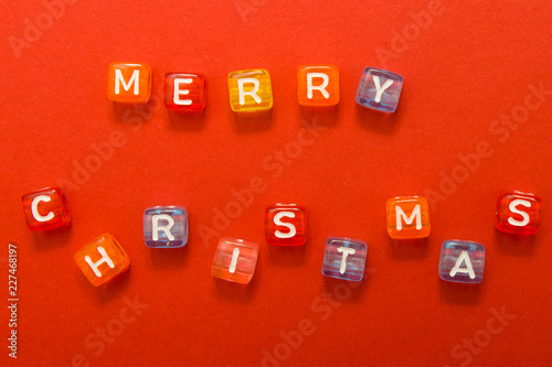words merry christmas made of colorful blocks on red background. Flat lay, top view - holidays, winter, christmas and new year celebration concept.