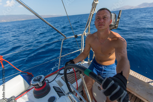 Man skipper steers the controls of a sailing yacht boat. © De Visu