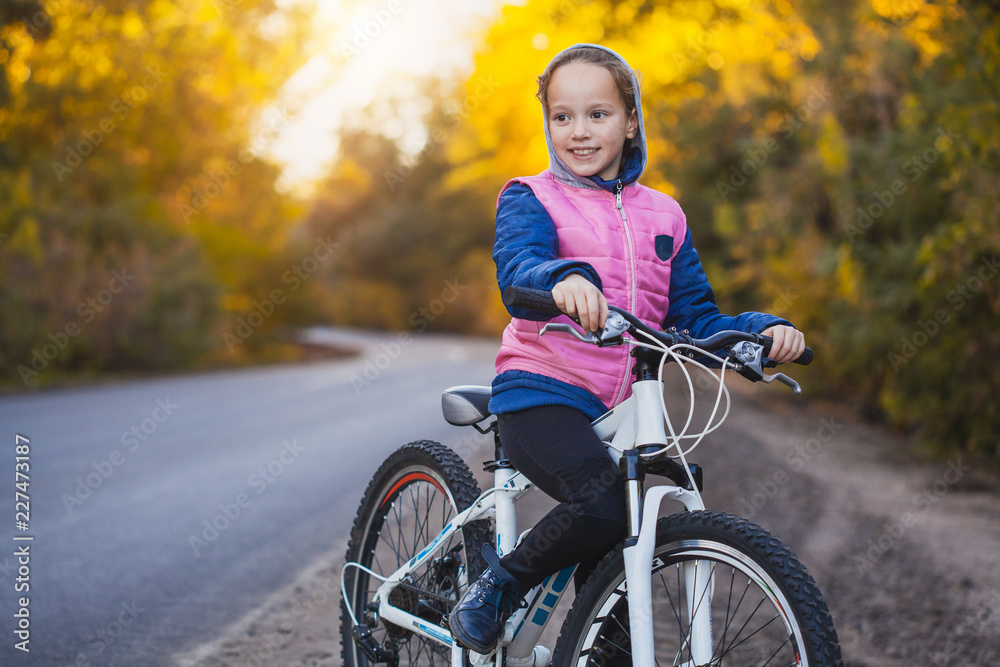 kid on a bicycle in the sunny autumn forest. girl cycling outdoors kid on a bicycle in the sunny autumn forest. girl cycling outdoors