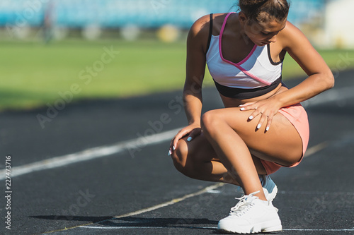 Young woman in sportswear sits on the track of the stadium after training. healthy lifestyle