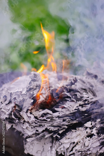 Paper burning on green summer grass outdoors.