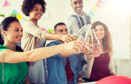 corporate, celebration and holidays concept - happy coworkers clinking bottles with non-alcoholic drinks at office party