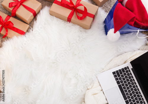 Christmas gift boxes, laptop and santa hat on white background