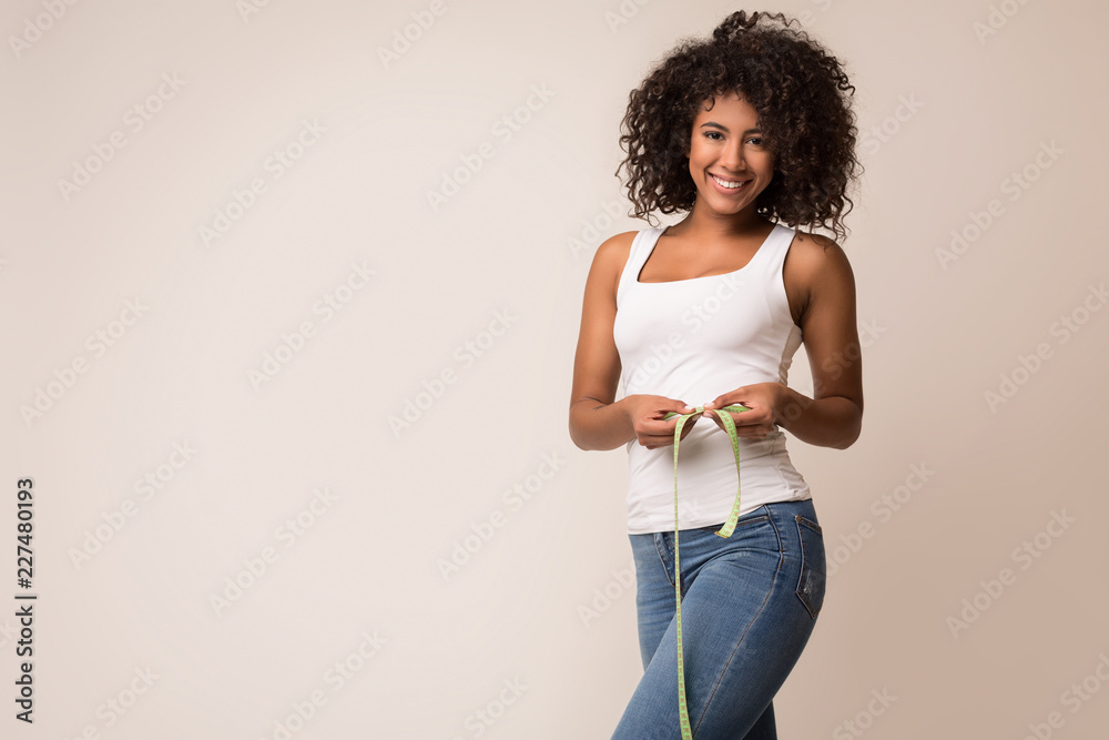Happy african-american woman measuring waist with tape - obrazy, fototapety, plakaty 