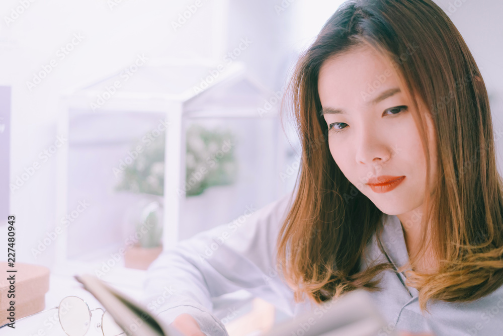 Portrait of asian young woman reading book on windowsill at home,A woman opening and reading a book in living room. Portrait of asian young woman reading book on windowsill at home,A woman opening and reading a book in living room.