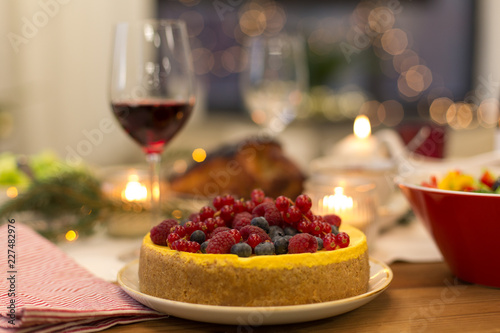 christmas dinner and eating concept - close up of berry cake and other food on table at home