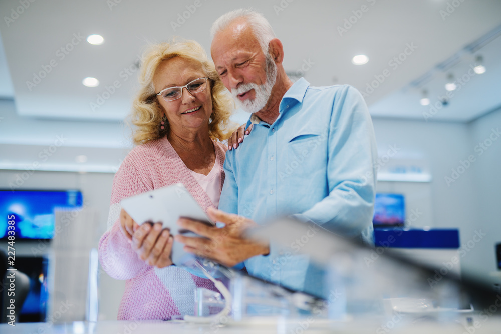Beautiful senior couple at tech store. Looking for a new tablet. Beautiful senior couple at tech store. Looking for a new tablet.
