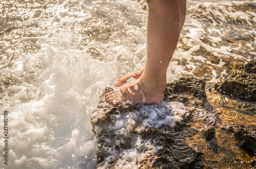 Naked female legs on a rocky cliff washed by sea foam © Michael Kachalov