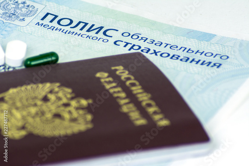 Close-up of Russian health insurance policy and Russian passport and a few pills
