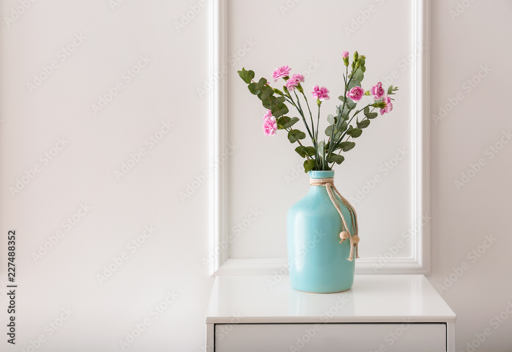 Vase with beautiful pink flowers on dresser near white wall Vase with beautiful pink flowers on dresser near white wall