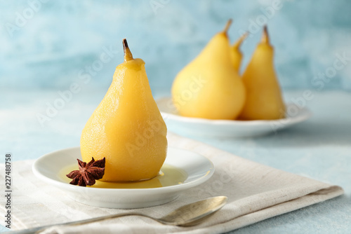 Plate with delicious poached pear in wine on color table