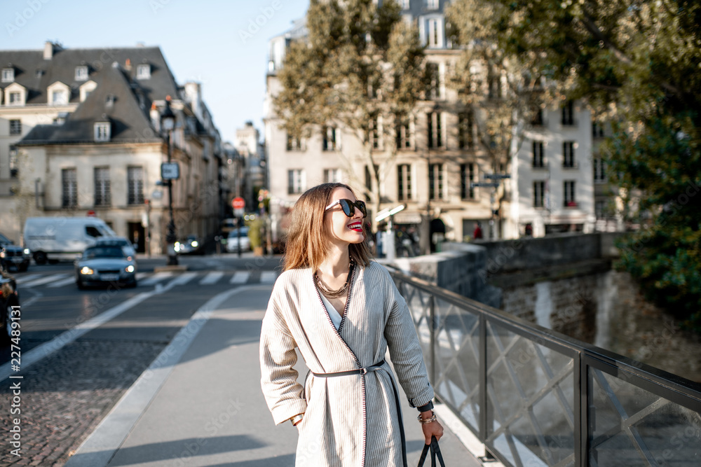 Lifestyle portrait of a stylish woman walking the street during the morning light in Paris, France