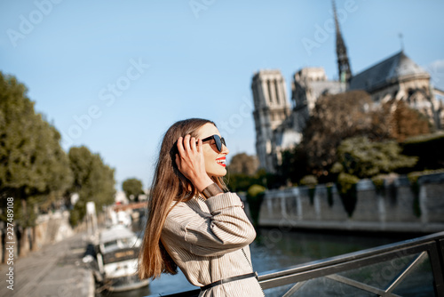 Lifestyle portrait of a young woman walking on the bridge with famous cathedral on the background in Paris, France © rh2010