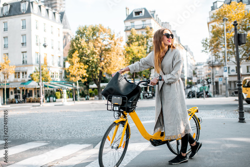 Photography Portrait of a young stylish woman with yellow bicycle on the street in Paris