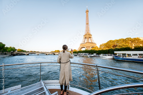 Young woman enjoying beautiful landscape view on the riverside with Eiffel tower from the boat during the sunset in Paris. Wide view with copy space