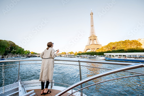 Young woman enjoying beautiful landscape view on the riverside with Eiffel tower from the boat during the sunset in Paris. Wide view with copy space © rh2010