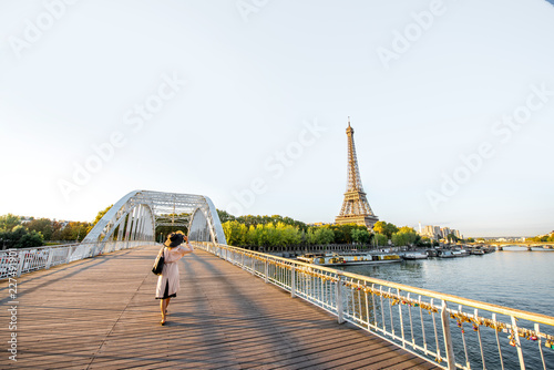 Fotografie, Tablou Landscape view on the river and Eiffel tower with woman walking on the footbridg