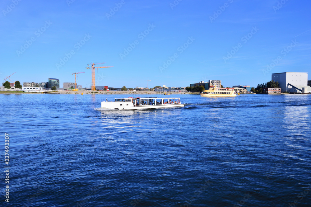 Rzeka Ij i budynki na brzegu w pogodny dzień. Rzeka Ij i budynki na brzegu w pogodny dzień.