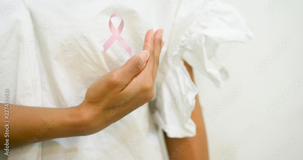 close up woman hand touching on chest with pink ribbon for breast cancer month concept close up woman hand touching on chest with pink ribbon for breast cancer month concept