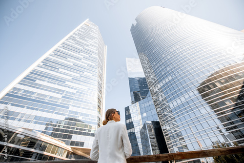 Portrait of a young business woman outdoors with high skyscrapers on the background