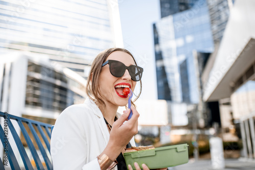 Foto Business woman having a snack with lunch box during a break sitting outdoors at