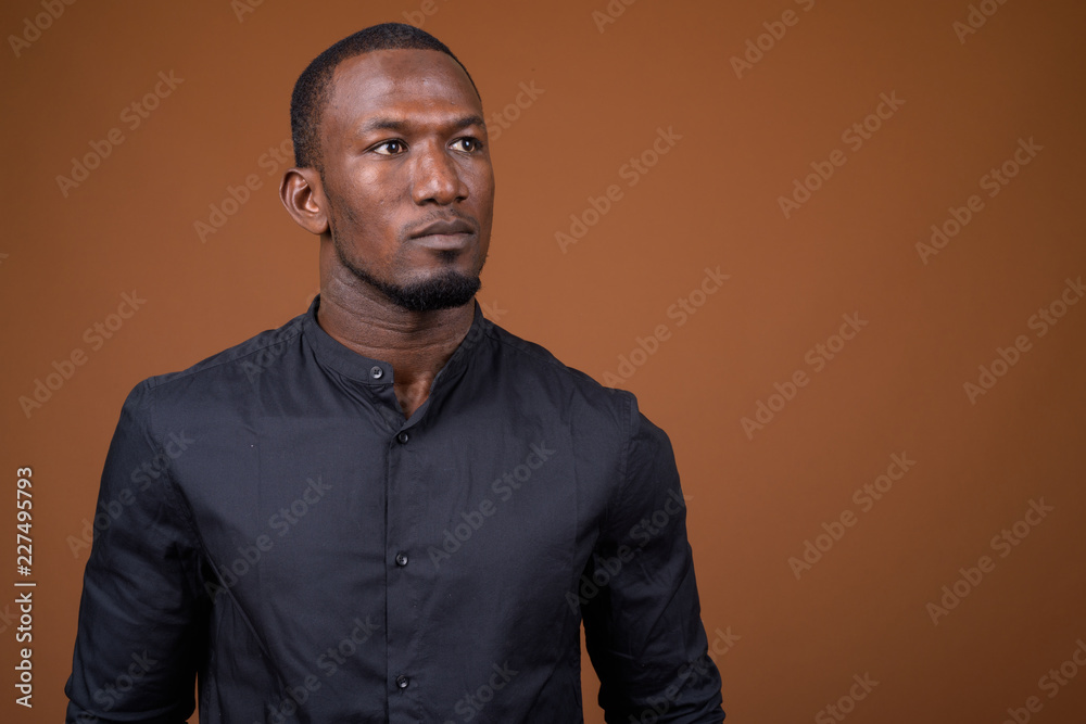 Portrait of handsome African businessman against brown background Portrait of handsome African businessman against brown background