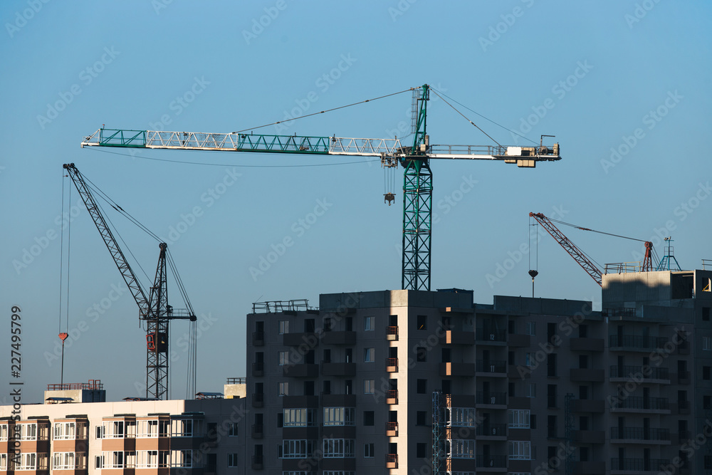 Construction of a residential high-rise building. Photo of a construction crane installing floor decks