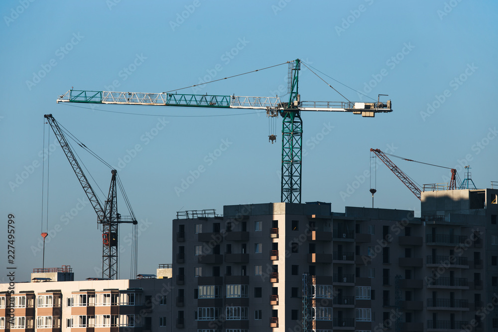 Construction of a residential high-rise building. Photo of a construction crane installing floor decks Construction of a residential high-rise building. Photo of a construction crane installing floor decks