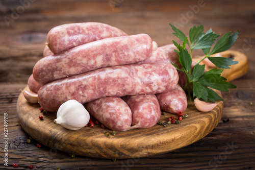 Fotografia Raw sausages on the wooden board