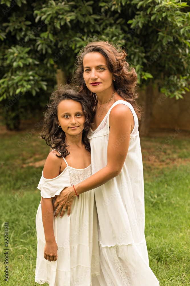 Beautiful mother and daughter in white dresses.