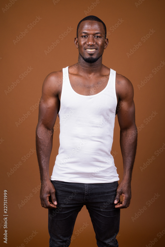 Handsome muscular African man against brown background Handsome muscular African man against brown background