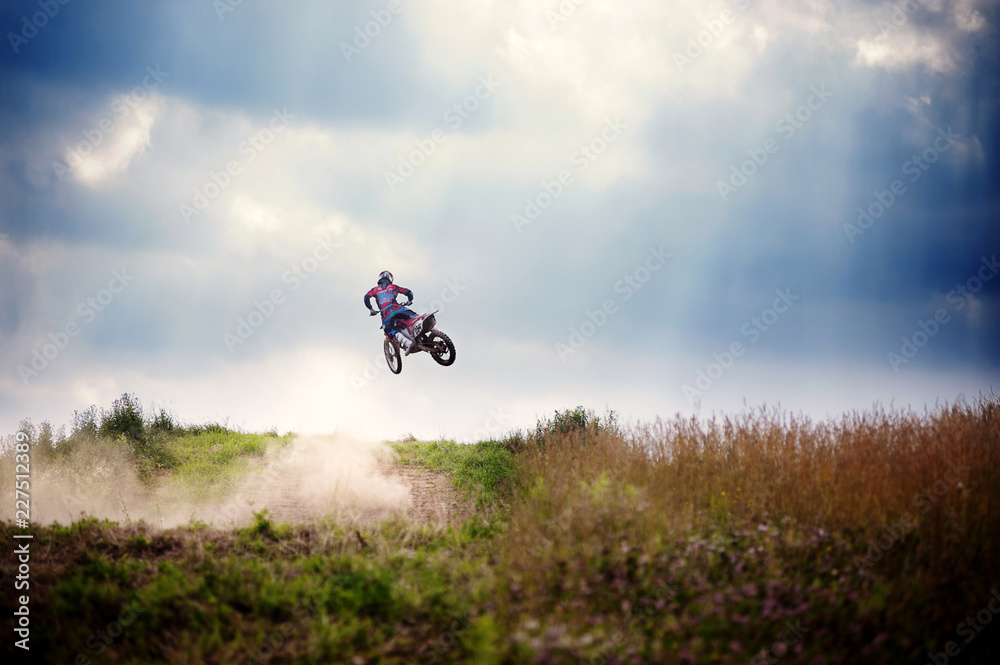 Obraz premium Biker performing stunt in mid air against cloudy sky