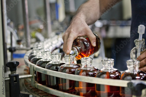 Man pouring liquid in whiskey bottles at distillery