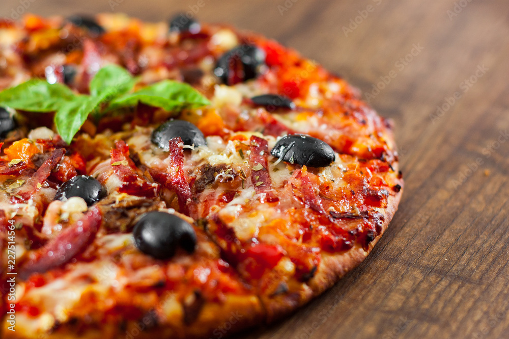 slices of Pizza with Mozzarella cheese, salami, pepper, ham, pepperoni, olives, Spices and Fresh Basil. Italian pizza on wooden background slices of Pizza with Mozzarella cheese, salami, pepper, ham, pepperoni, olives, Spices and Fresh Basil. Italian pizza on wooden background
