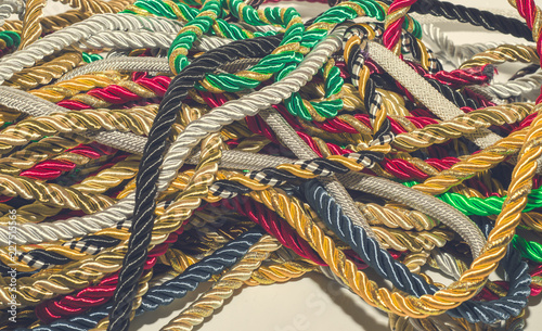 Multi-colored decorative rope scattered in a mess. Textile manufacture, threads, decor.