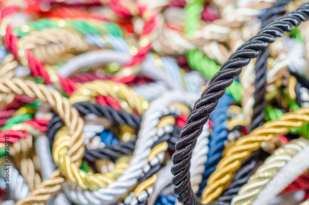 Multi-colored braided decorative laces scattered in a mess. Textile manufacture, threads, decor.