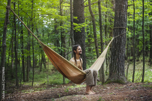 Fotografie Man relaxing on hammock in forest