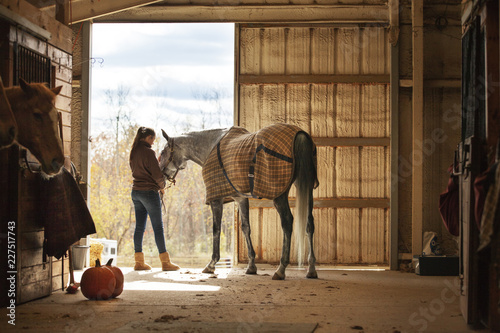 Foto Teenage girl standing with horse in stable