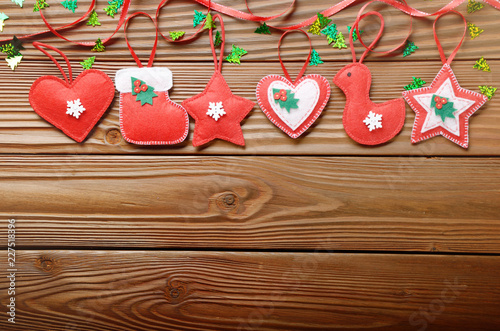 Handmade rustic red felt Christmas tree decorations flat lying on wooden table