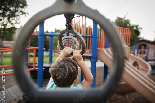 Schilderij op canvas Boy hanging from monkey bars at playground