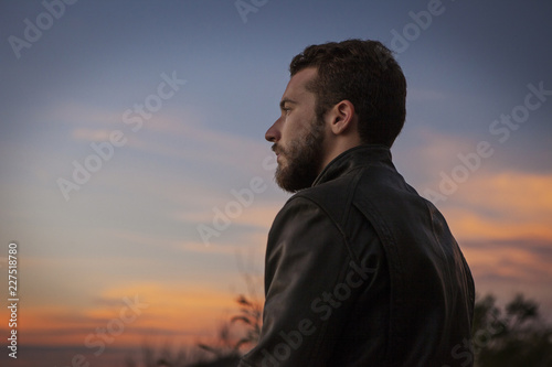 Low angle view of handsome man looking away while standing against sky
