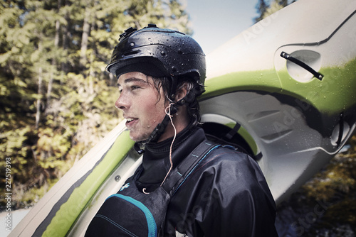 Man looking away while carrying kayak