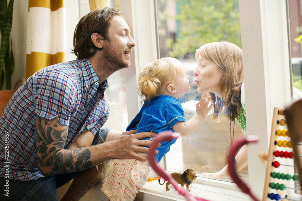 Obraz premium Father holding daughter while looking at mother through window