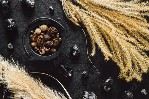 Black Cauldron with Seeds and Obsidian on Black Table with Dried Feather Grass photo