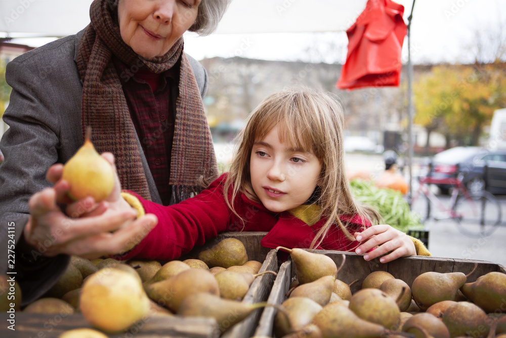 Fototapeta premium Family examining pears in market